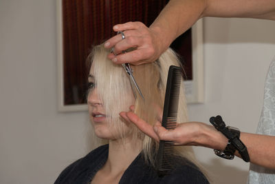 Hairdresser cutting woman hair at salon