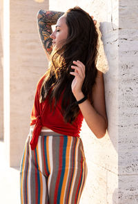 Young woman standing against wall