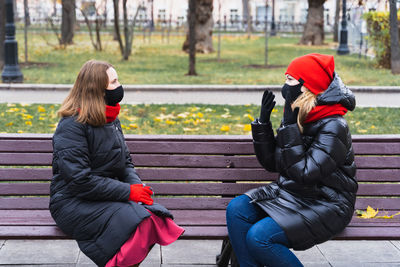 Woman sitting on bench in park during winter