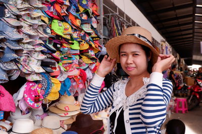 Side view of woman buying hat at market stall