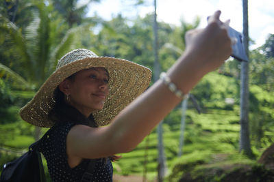 Teen girl wearing a big straw hat taking selfies using mobile phone