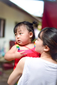 Close-up of mother carrying daughter at home