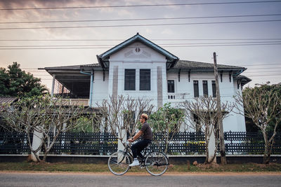 Man sitting on bicycle by building