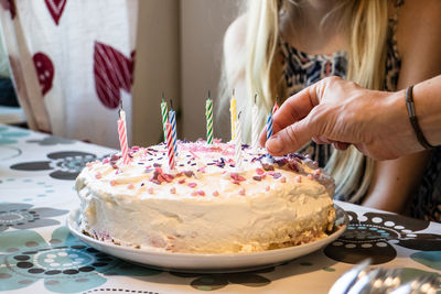 Close-up of hand putting candles on birthday cake
