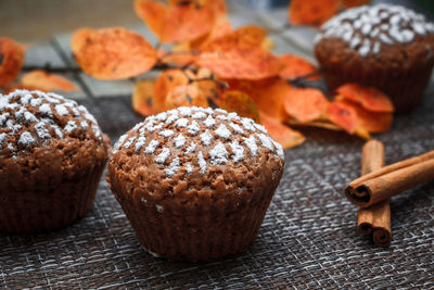 Chocolate muffins with apple filling on a background of autumn leaves and cinnamon