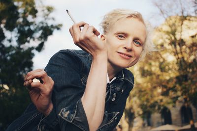 Portrait of woman smoking cigarette against trees