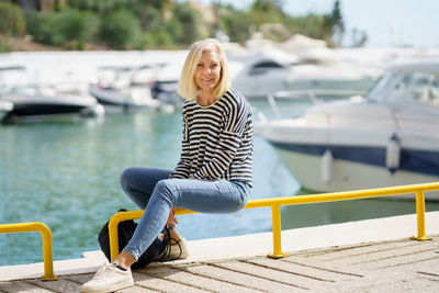 Portrait of young woman sitting on railing