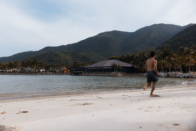 Rear view of woman standing at beach