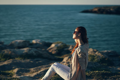 Side view of woman standing on rock at sea shore