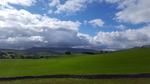 Scenic view of grassy field against cloudy sky