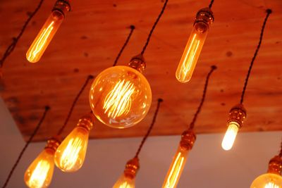 Low angle view of illuminated light bulbs hanging from ceiling