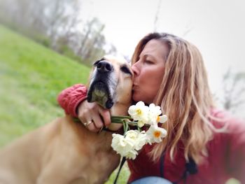 Midsection of woman with dog against pink flowers