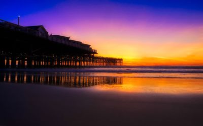 Pier by sea against sky during sunset