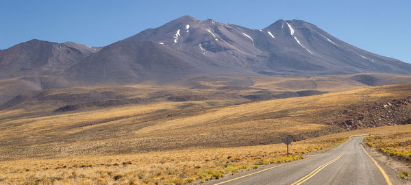 Scenic view of road by mountains against sky