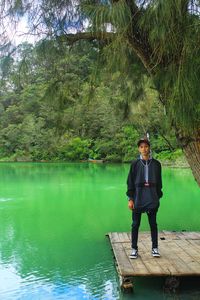 Full length of man standing by lake against trees