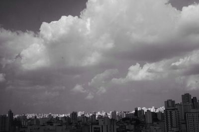 Buildings in city against cloudy sky