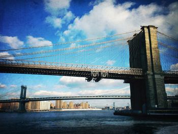 Low angle view of brooklyn bridge against cloudy sky