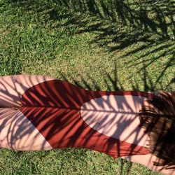 Midsection of seductive woman relaxing on grassy field during sunny day