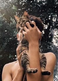 Midsection of shirtless woman with cat