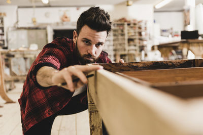 Man examining wood in workshop
