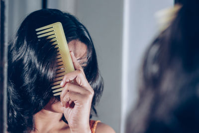 Reflection of woman combing hair on mirror