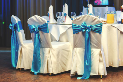 Empty white wedding chairs decorated blue bows at restaurant