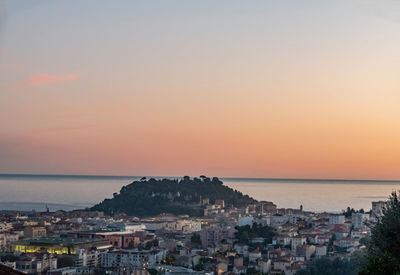 High angle view of townscape by sea against sky during sunset