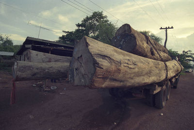 Abandoned truck on road by trees against sky