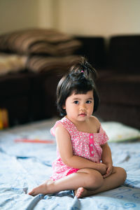 Portrait of a girl sitting on bed at home