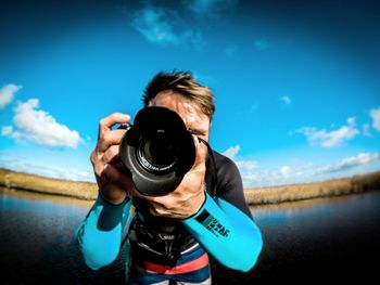 Portrait of woman photographing against sky