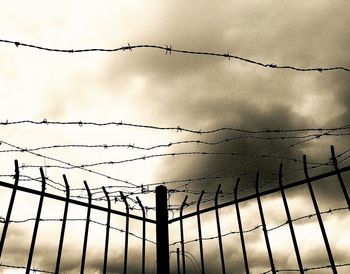 Low angle view of barbed wire fence against sky