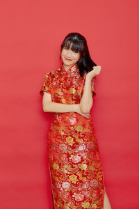 Portrait of a smiling young woman against red background