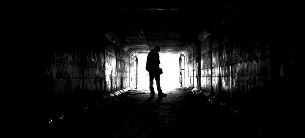 Rear view of silhouette woman walking in tunnel