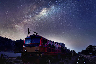 Train on railroad tracks against sky at night