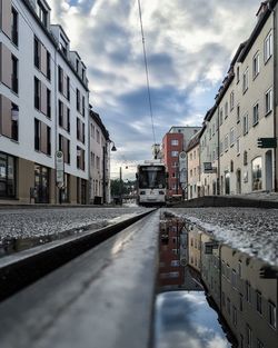 Reflection of buildings on puddle against cable car on street