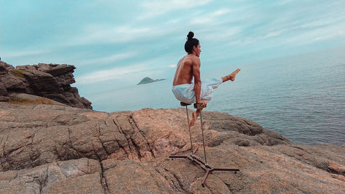 Young adult man doing circus acrobatics handstand on mountain in brazil during day light