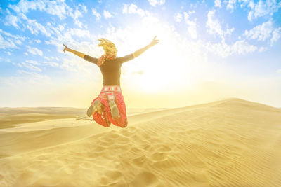 Woman jumping at beach against sky
