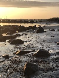 Surface level of rocks on beach against sky during sunset