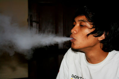 Young man looking away while smoking cigarette