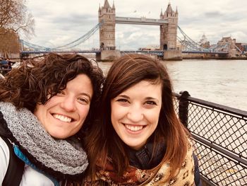Portrait of smiling friends in city with bridge in background