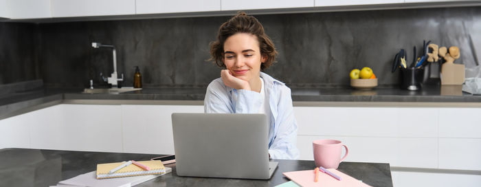 Portrait of young woman using laptop at home