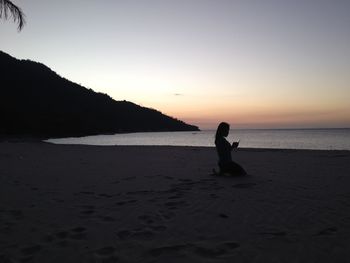 Silhouette person on beach against clear sky