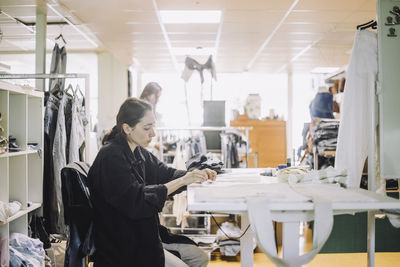 Side view of female fashion designer working at workshop