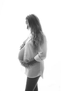 Side view of woman standing against white background