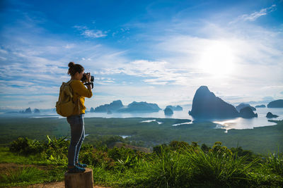 Man photographing at camera against sky