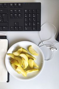 High angle view of fruit in plate by laptop on table