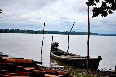 Boats in calm sea against cloudy sky