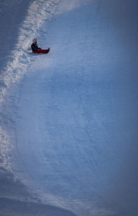 High angle view of boy sitting on snow covered field