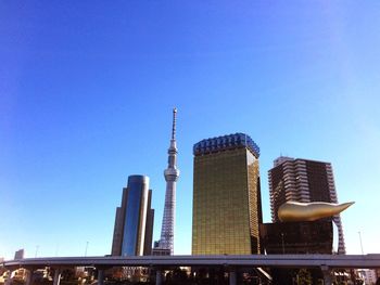 Low angle view of tokyo skytree and skyscrapers against clear blue sky