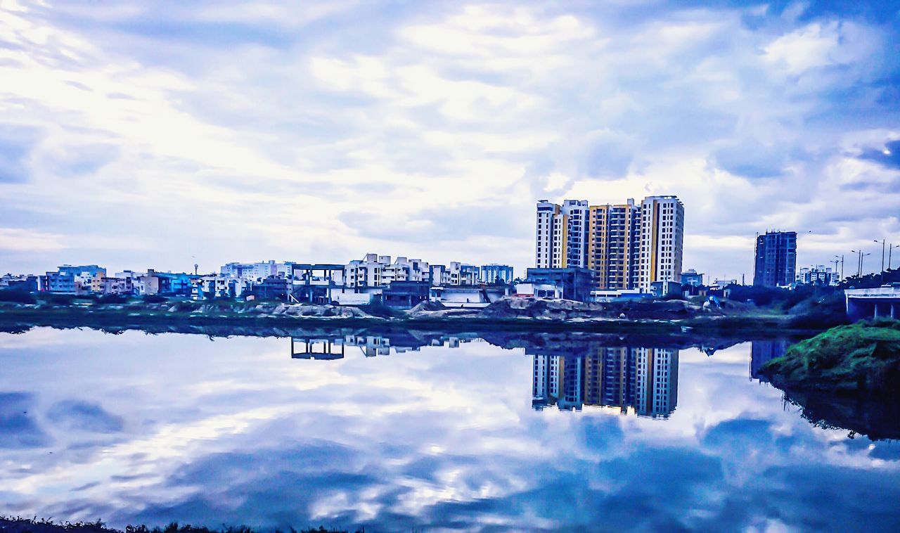 reflection, water, architecture, built structure, building exterior, waterfront, city, residential building, calm, sky, standing water, lake, cloud - sky, symmetry, travel destinations, cloud, residential district, day, apartment, tranquility, water surface, scenics, cloudscape, bridge, reflection lake, no people, tranquil scene